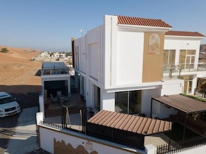 A modern two-story building with a flat roof, large windows, and a balcony.
