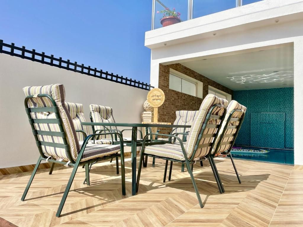 Une terrasse avec une table et des chaises, un pot de fleurs et une vue sur le ciel.