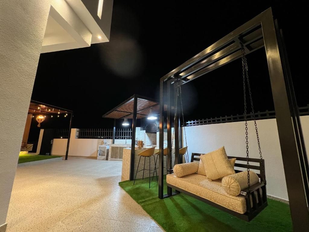 Un espacio al aire libre con sillón colgante, barra y un conjunto de asientos.