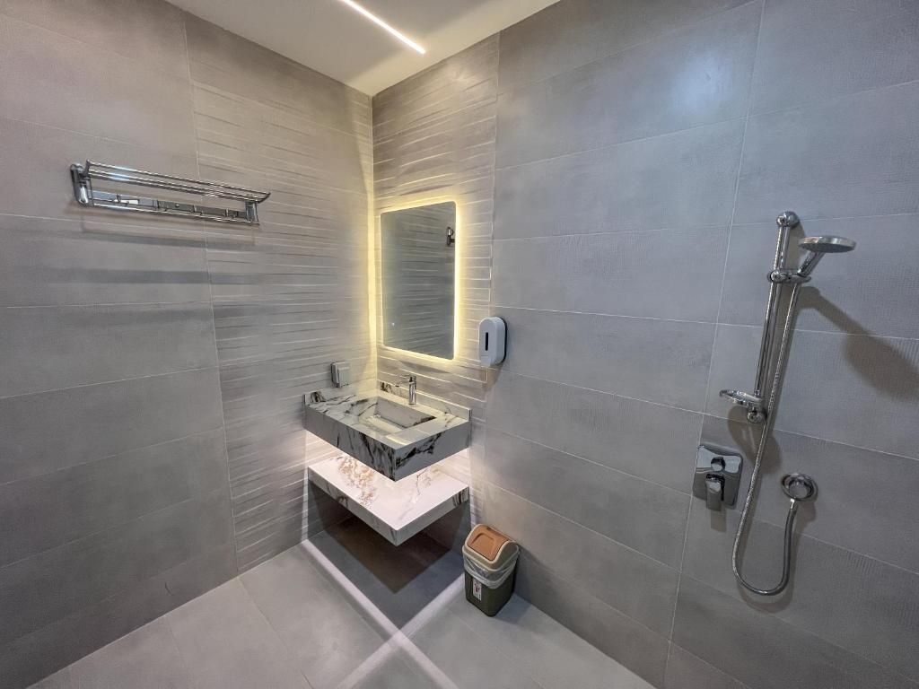 Un baño moderno con lavamanos de mármol, cabina de ducha con mampara de vidrio y un perchero para toallas.