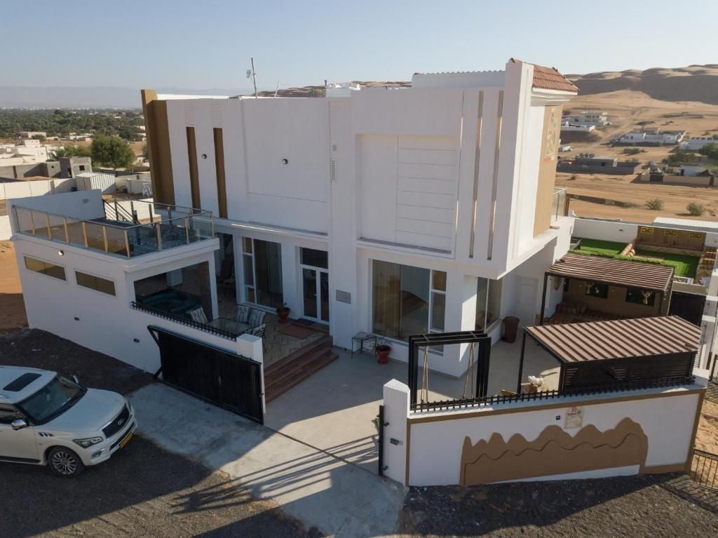 A modern two-story house with a garage, a balcony, and a view of the surrounding landscape.