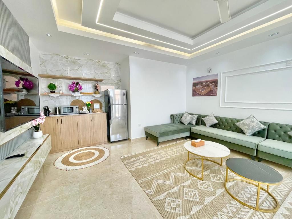 Una sala de estar moderna con sofá, mesa de centro y zona de cocina con armarios y electrodomésticos.