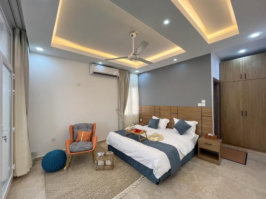 Een moderne slaapkamer met een bed, een stoel, een garderobe en een plafondventilator.