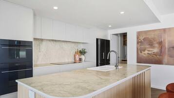 A modern kitchen with a marble countertop, stainless steel appliances, and a wooden island.