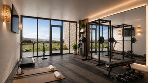 Et fitnessrum med træningsudstyr, et løbebånd og et stort spejl der afspejler rummet.