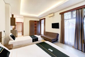A hotel room with a bed, a sofa, a TV, a wardrobe, and a window with curtains. - Spacious Family Suite With Free Wifi and Parking (Denpasar)