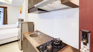 A compact kitchenette with a gas stove, a sink, and a built-in oven. - Spacious Family Suite With Free Wifi and Parking (Denpasar)