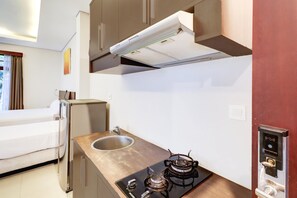 A compact kitchenette with a gas stove, a sink, and a built-in oven. - Spacious Family Suite With Free Wifi and Parking (Denpasar)