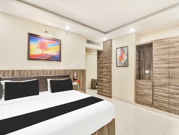 A modern bedroom with a large bed, a painting, a wardrobe, and a nightstand.