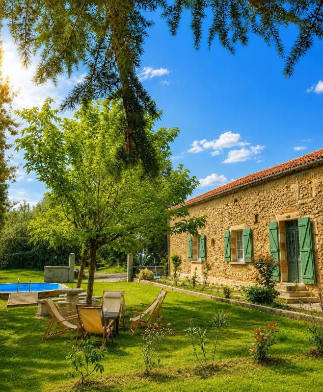 A stone building with a red-tiled roof, a swimming pool, and a lawn with chairs.