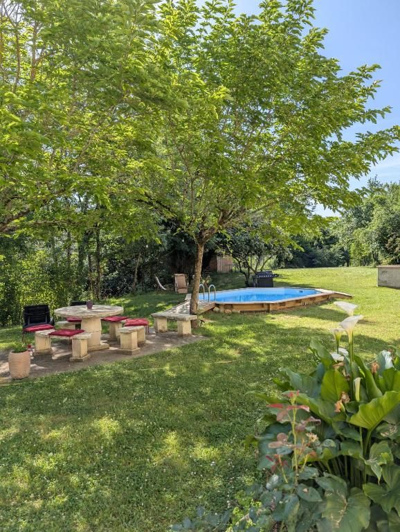 Un patio trasero con piscina, mobiliario exterior y un árbol.