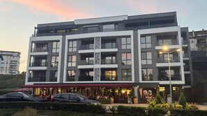 A multi-story hotel with a central atrium, outdoor seating, and a landscaped area. - Central Park View Apartment with a terrace and lake views features (Dobrich)