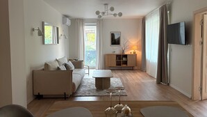 A modern living room with a sofa, a coffee table, and a TV. - Central Park View Apartment with a terrace and lake views features (Dobrich)