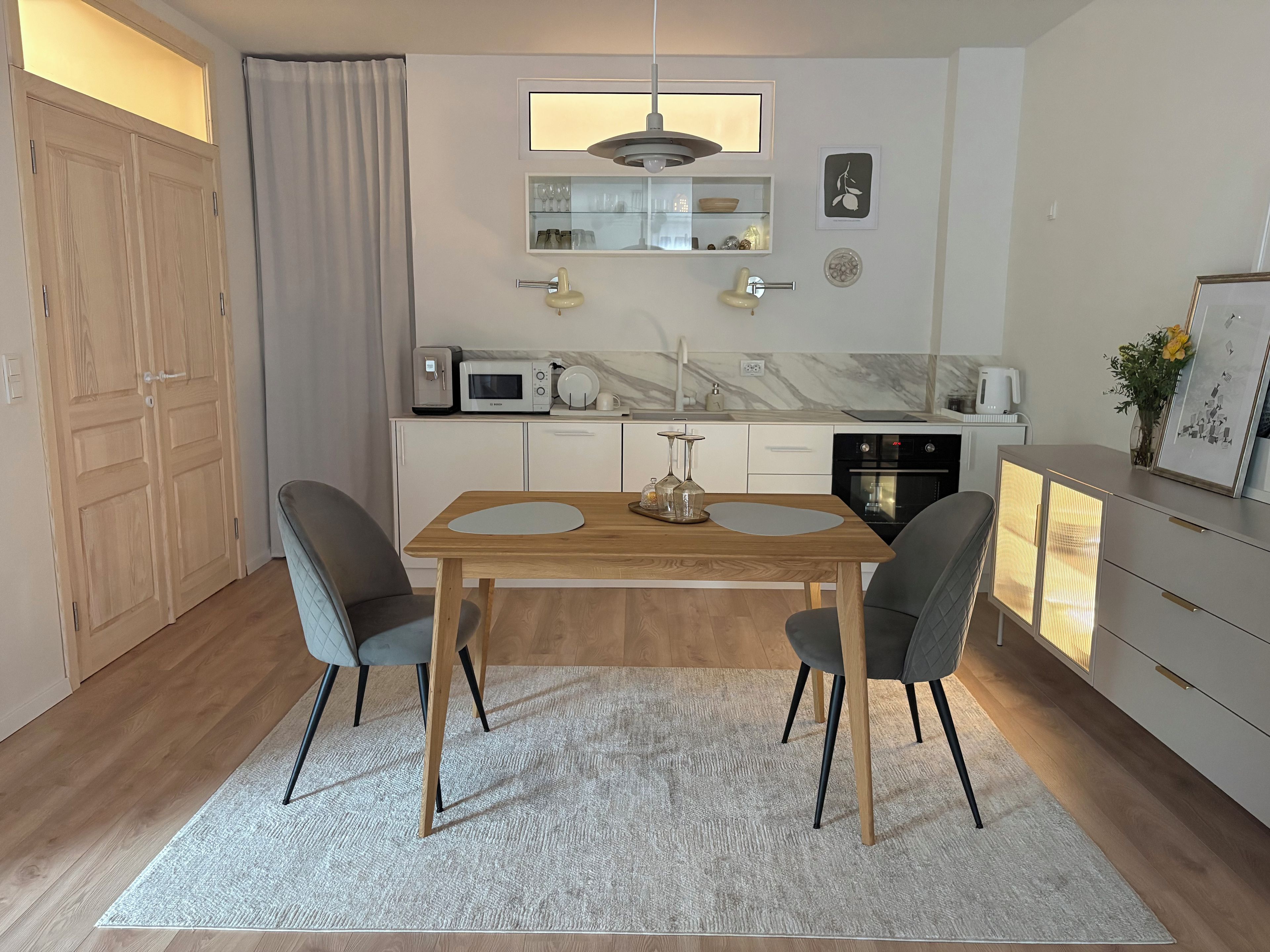 Une cuisine moderne avec un coin repas, des meubles en bois, un four à micro-ondes et une machine à café.