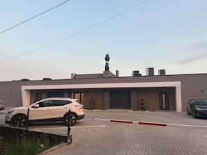 A modern building with a garage, a parked SUV, and a clear sky.