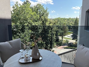 Un balcon avec une table ronde, un vase rempli de fleurs et un ensemble de verres.