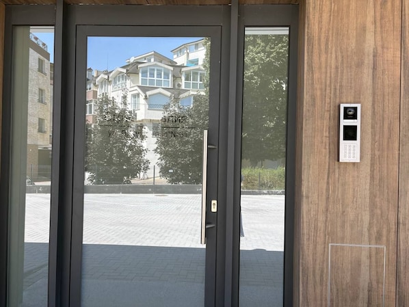 Une porte dotée d’un clavier pour le verrouillage et donnant sur un immeuble avec de nombreuses fenêtres et des balcons.
