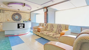 A hotel reception area with a sofa, a reception desk, and a wall-mounted clock. - OYO Kurnool Formerly Sai Priyanka Inn (Kurnool)
