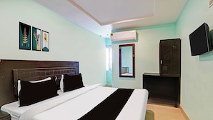 A hotel room with a bed, a television, a wardrobe, and artwork on the wall. - OYO Kurnool Formerly Sai Priyanka Inn (Kurnool)