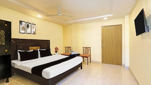 A hotel room with a bed, a chair, a television, and a door. - OYO Kurnool Formerly Sai Priyanka Inn (Kurnool)