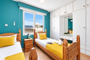 A bedroom with two beds, a wardrobe, a bedside table, and a window with a view. - 2BR Apartment with Pool - Aphrodite by Premier (Ayia Napa)