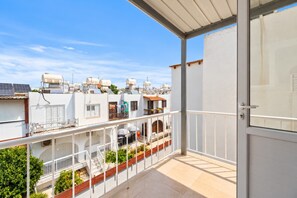 Ein Balkon mit Blick auf angrenzende Gebäude, einer Tür und einem Geländer.