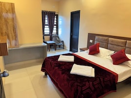Habitación de hotel con una cama grande, dos almohadas, una silla, un escritorio y una ventana con cortinas.