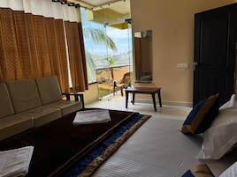 Habitación de hotel con cama, sofá, una mesita y vistas al exterior.