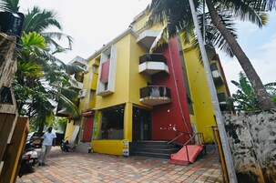 Un edificio de varios pisos con fachada amarilla, detalles en rojo y una escalera que lleva a la entrada.
