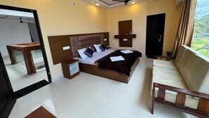 A hotel room with a bed, bedside table, and a window with curtains. - KVK Beach Residency (Murdeshwar)