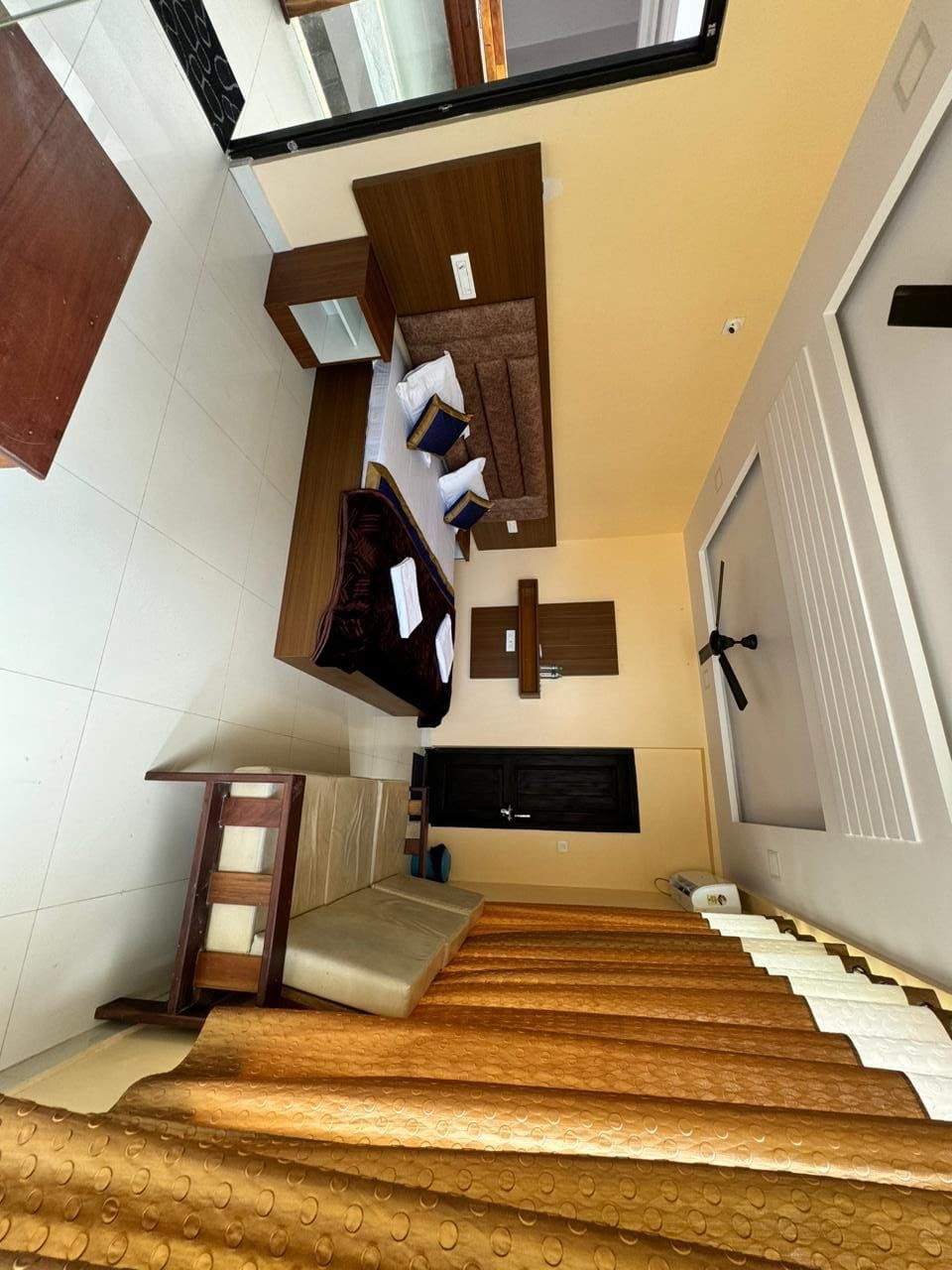 A staircase leading to a room with a bed, a wooden bench, and a wall-mounted shelf.