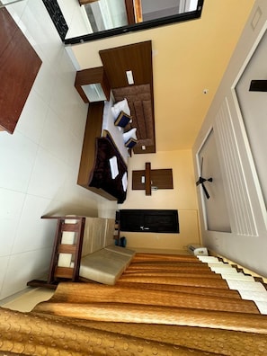 A staircase leading to a room with a bed, a wooden bench, and a wall-mounted shelf.