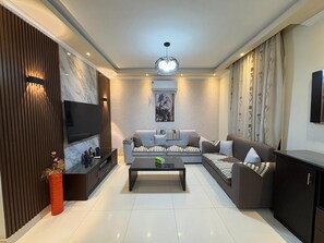 A modern living room with a flat-screen TV, a sofa set, a coffee table, and a cabinet. - Modern 2BR Apartment in Rehab (Cairo Governorate)