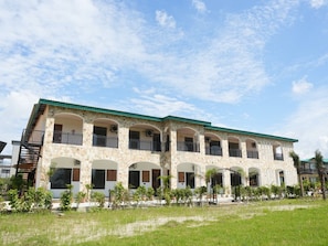 A multi-story building with balconies, a staircase, and a green roof. - Hotel Oriva (Aligarh)