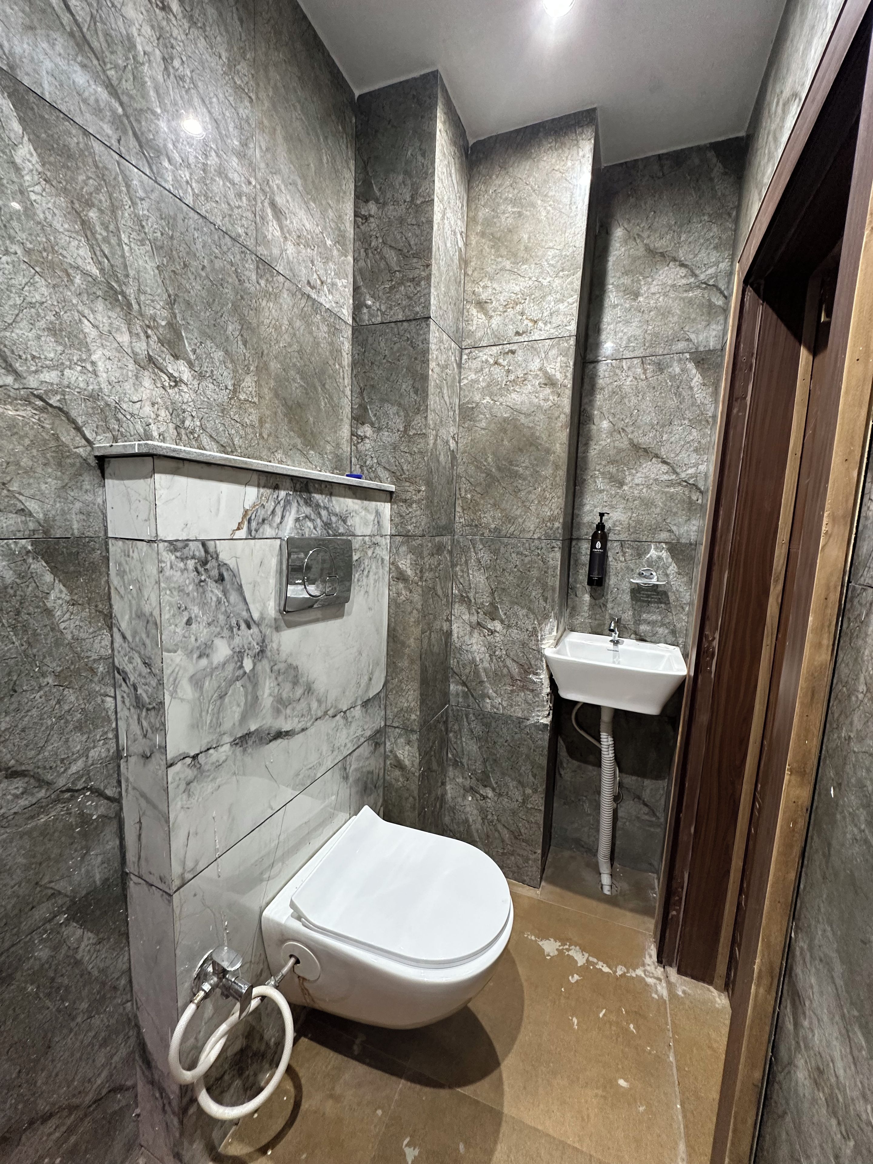 Un baño con inodoro, lavamanos y paredes de mármol.