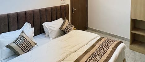 A bedroom with a bed, a ceiling fan, recessed lighting, a door, and a wardrobe.