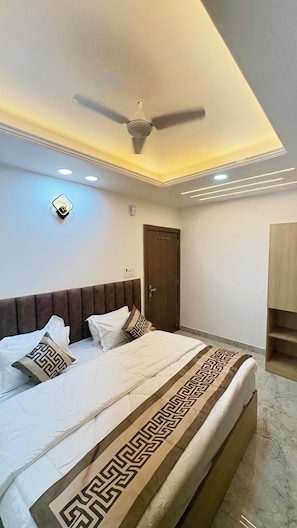 A bedroom with a bed, a ceiling fan, recessed lighting, a door, and a wardrobe.