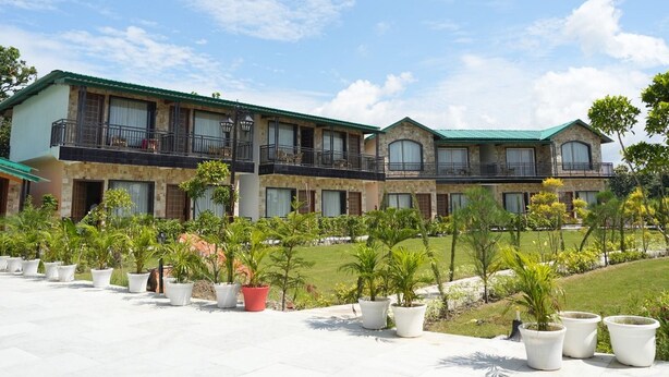 A hotel with multiple balconies, a courtyard with potted plants, and a clear sky. - Hotel Oriva (Aligarh)