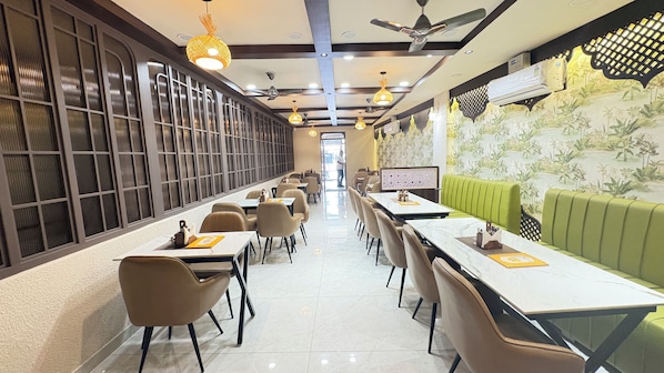 A restaurant with long tables, chairs, and a green booth area.