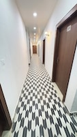 Un pasillo con piso estampado, puertas y luces fijadas a la pared.