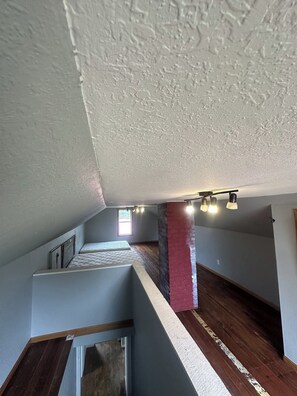 A room with a sloped ceiling, a red brick column, and a wooden floor. - Rustic Farmhouse on Working WI Wedding Venue (Sparta)