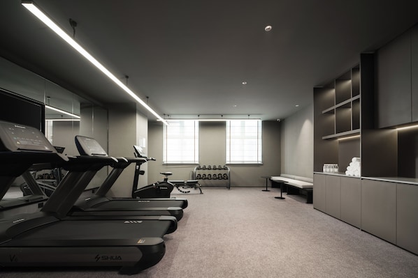 A modern gym with treadmills, dumbbells, and a bench.
