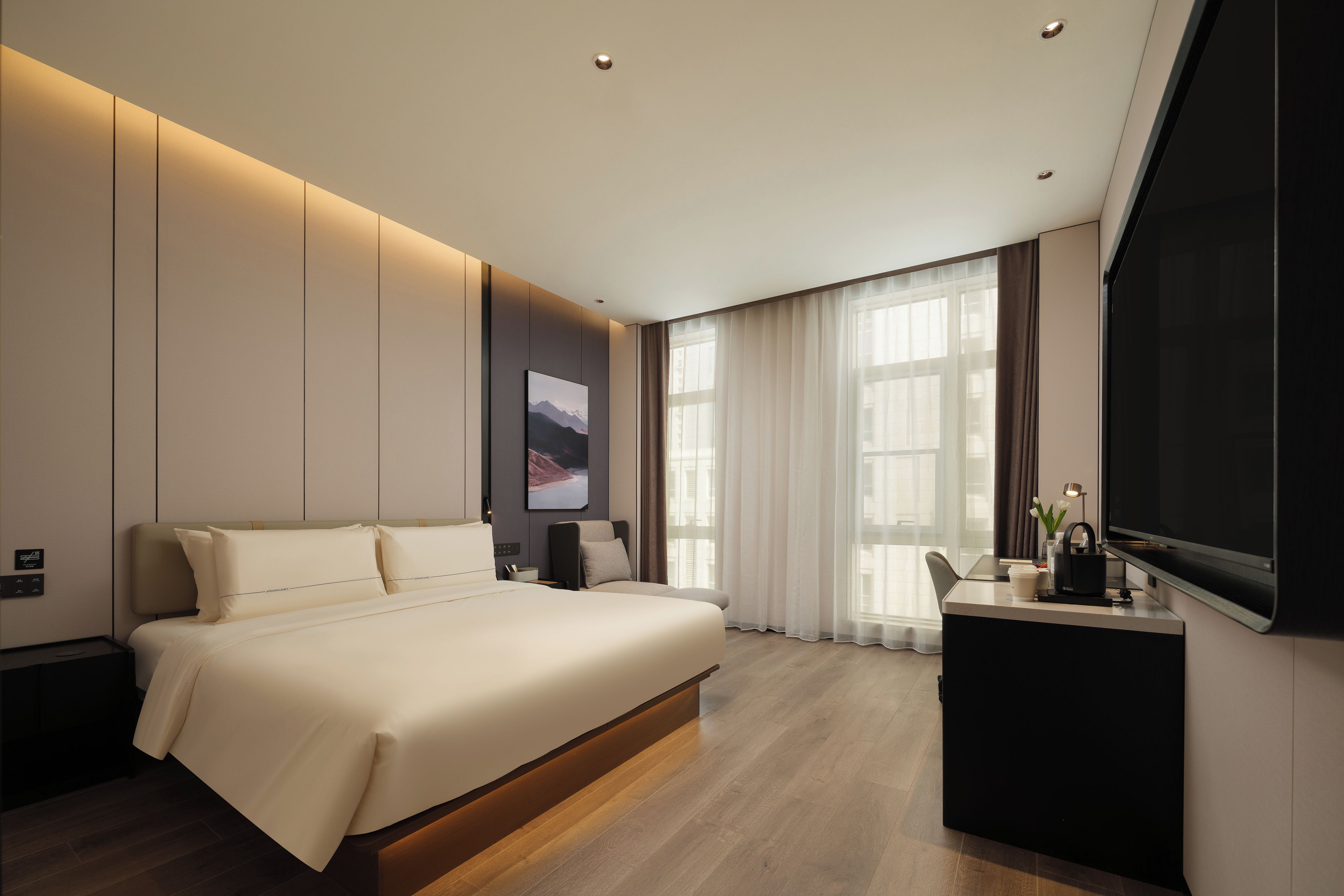 Una habitación de hotel moderna con una cama grande, un escritorio y un televisor de pantalla plana.
