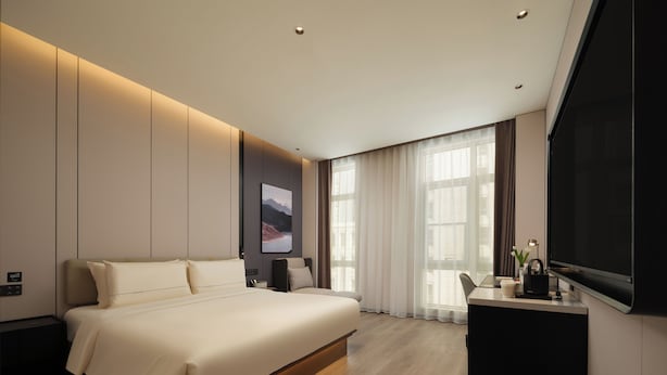 A modern hotel room with a large bed, a desk, and a flat-screen TV. - AtourHotelDalianXinghaiSquareRoosevelt (Dalian City)
