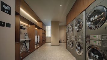 A modern laundry facility with multiple washing machines, a drying station, and a neatly organized storage area with shelves.