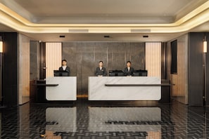 A reception area with two receptionists at marble counters, a modern interior design, and a polished floor.