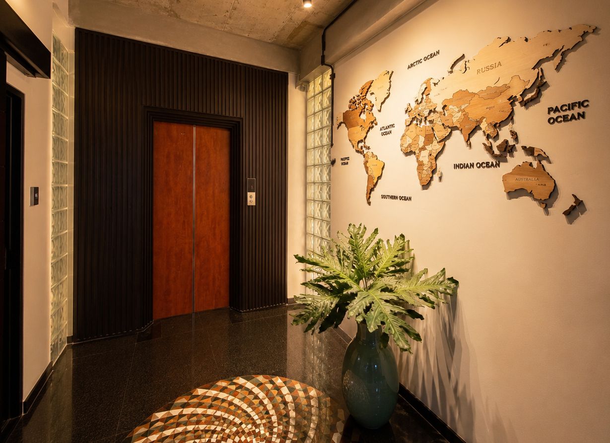 A hallway with a wooden door, a world map on the wall, and a potted plant.