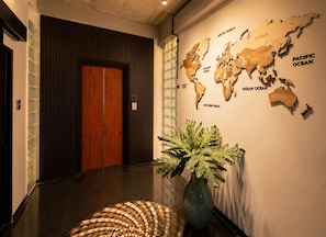 Un pasillo con una puerta de madera, un mapa mundial en la pared y una planta en maceta.