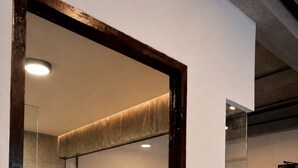 Un baño moderno con cabina de ducha de vidrio, un lavabo blanco y un espejo grande.