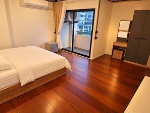 Une chambre d’hôtel comprenant un lit, un petit bureau, une armoire et une porte-fenêtre coulissante donnant sur un balcon.